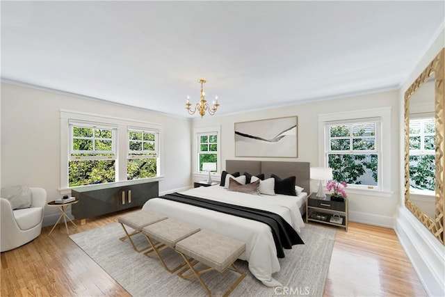 bedroom with crown molding, light wood-type flooring, an inviting chandelier, and multiple windows