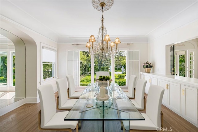 dining room featuring plenty of natural light, dark hardwood / wood-style flooring, ornamental molding, and a notable chandelier