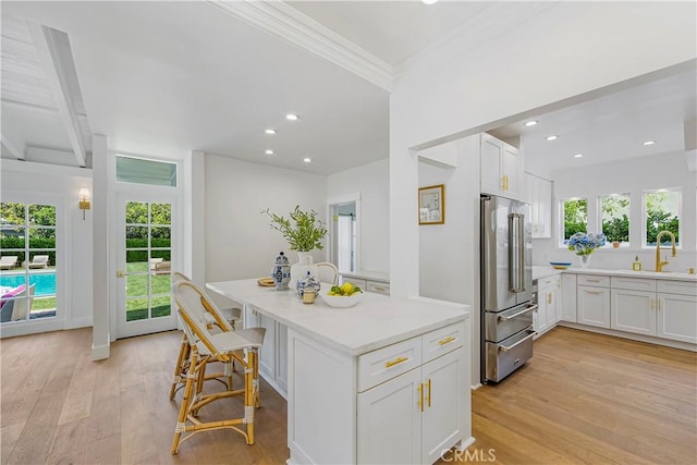 kitchen with a healthy amount of sunlight, light wood-type flooring, high end refrigerator, and white cabinetry