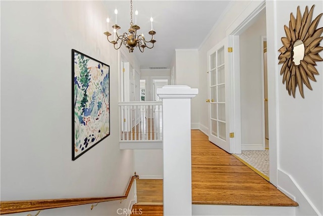 corridor featuring a notable chandelier, crown molding, and hardwood / wood-style floors