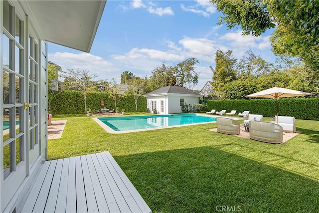 view of swimming pool featuring a lawn and an outdoor structure