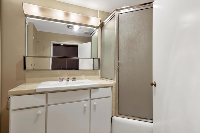 bathroom featuring vanity, backsplash, and combined bath / shower with glass door