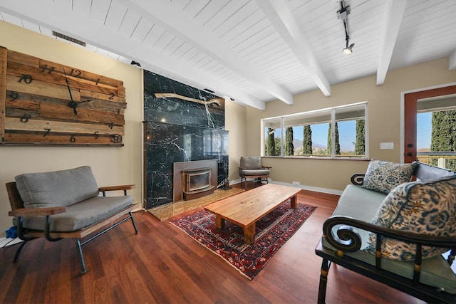 living room with beamed ceiling, a wood stove, hardwood / wood-style floors, and track lighting