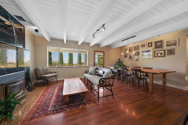 living room featuring dark wood-type flooring, wood ceiling, beam ceiling, and a wood stove