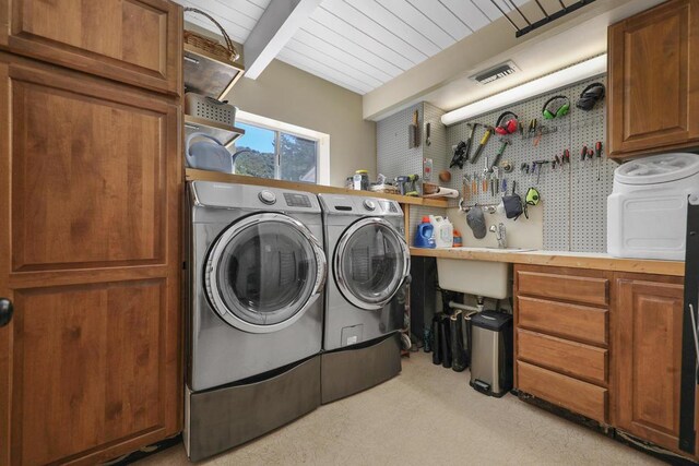 laundry area with washer and clothes dryer, a workshop area, and cabinets