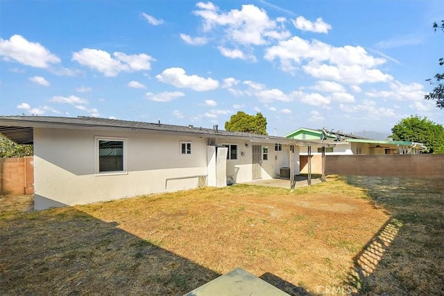 back of house with a lawn and a patio