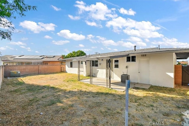 back of property with central AC unit, a patio area, and a yard