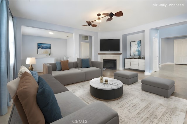 living room featuring a tiled fireplace, hardwood / wood-style flooring, and ceiling fan