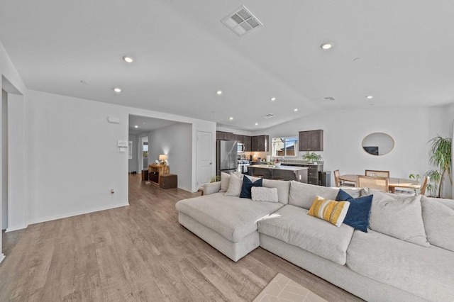 living room with light hardwood / wood-style floors and vaulted ceiling