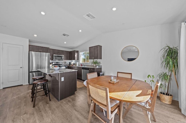 dining area featuring sink, light hardwood / wood-style floors, and vaulted ceiling