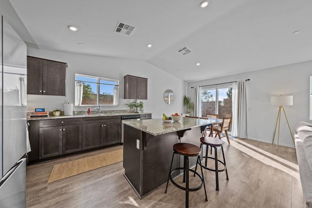 kitchen with a center island, sink, light hardwood / wood-style flooring, a breakfast bar, and lofted ceiling