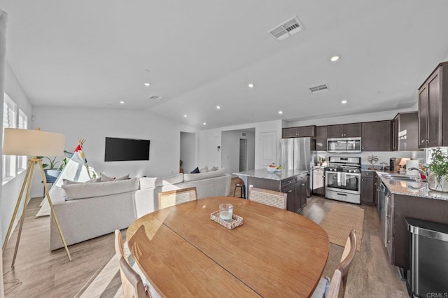 dining room with sink, light hardwood / wood-style flooring, and lofted ceiling