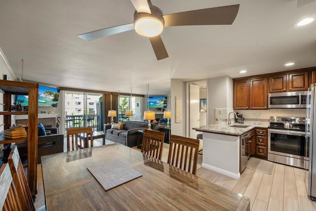 interior space featuring kitchen peninsula, appliances with stainless steel finishes, decorative backsplash, light stone countertops, and sink