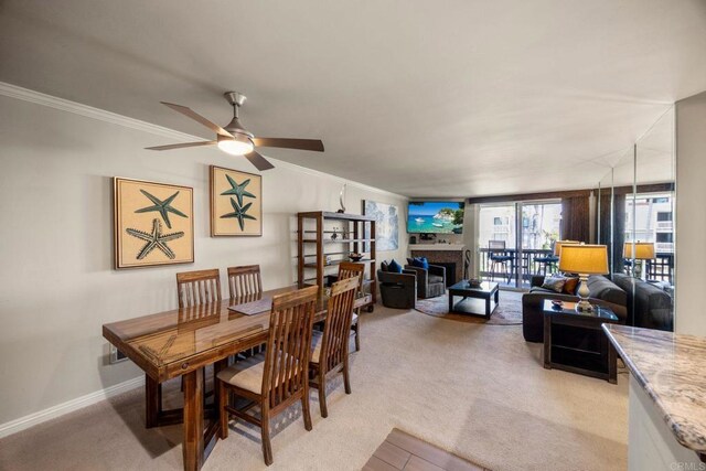 dining area with ceiling fan, light colored carpet, and ornamental molding