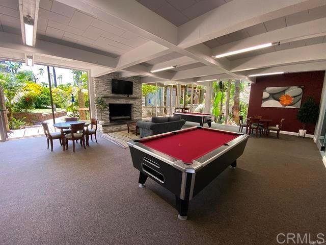 recreation room with beam ceiling, a stone fireplace, and billiards