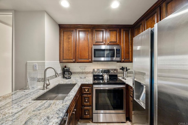 kitchen with tasteful backsplash, light stone countertops, sink, and stainless steel appliances