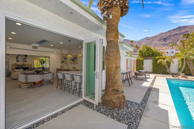 view of patio with a mountain view, exterior bar, and a fenced in pool