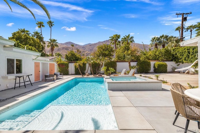 view of swimming pool featuring a mountain view, a patio area, and an in ground hot tub