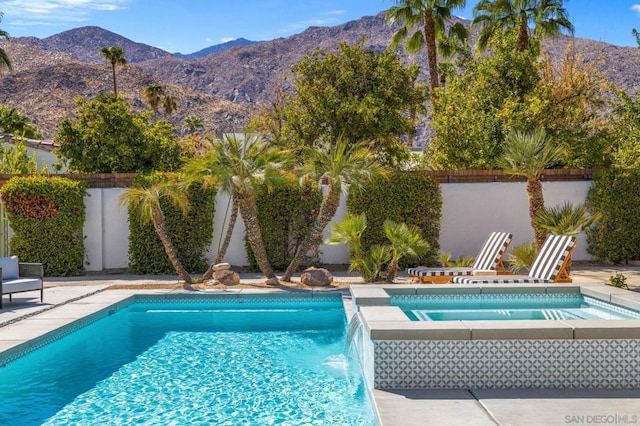 view of swimming pool with pool water feature, a patio area, a mountain view, and an in ground hot tub