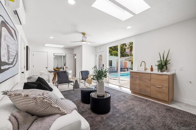 living room with ceiling fan, a wall mounted AC, and sink