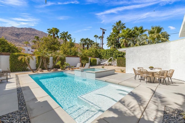 view of swimming pool featuring a mountain view, a patio, and an in ground hot tub