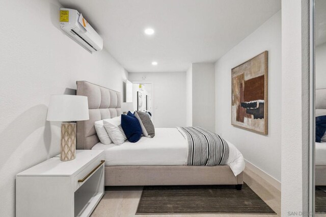 bedroom with light hardwood / wood-style flooring and a wall mounted air conditioner