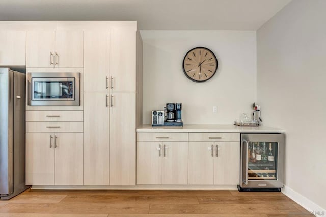 kitchen with light hardwood / wood-style floors, beverage cooler, and appliances with stainless steel finishes