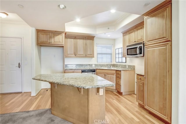 kitchen with a center island, a raised ceiling, a kitchen bar, ornamental molding, and stainless steel appliances