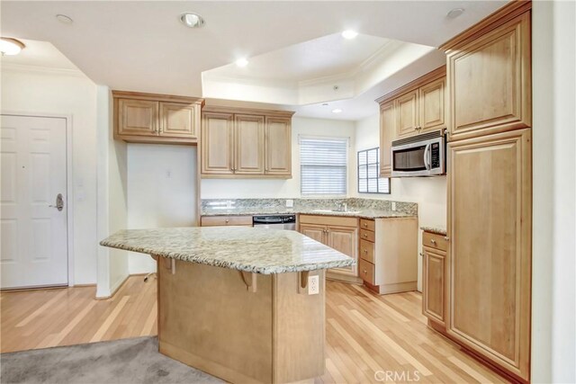 kitchen featuring stainless steel microwave, light stone countertops, a tray ceiling, and ornamental molding