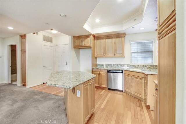 kitchen featuring a center island, stainless steel dishwasher, a raised ceiling, a breakfast bar area, and light brown cabinetry