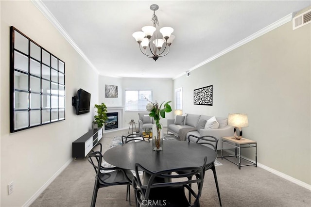 carpeted dining space with a glass covered fireplace, baseboards, visible vents, and ornamental molding