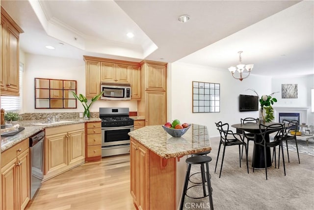 kitchen featuring a breakfast bar area, a kitchen island, a sink, stainless steel appliances, and crown molding