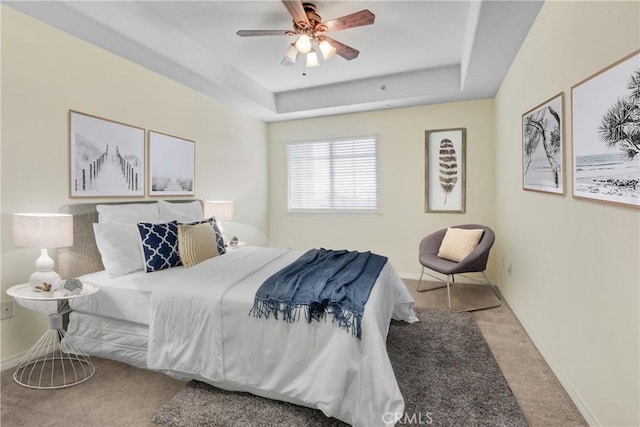 bedroom with baseboards, a raised ceiling, carpet floors, and a ceiling fan