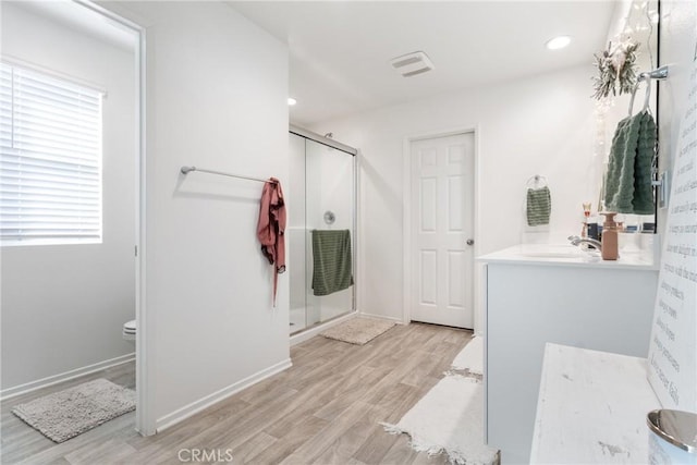 bathroom featuring wood-type flooring, toilet, a shower with door, and vanity