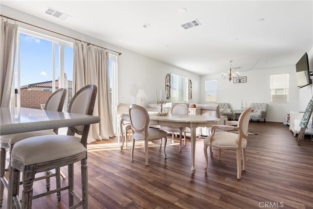 dining area featuring a healthy amount of sunlight, dark hardwood / wood-style floors, and a notable chandelier