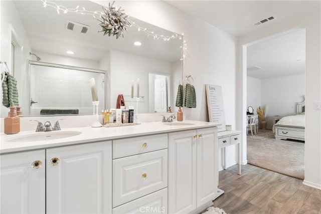 bathroom featuring an enclosed shower, vanity, and wood-type flooring