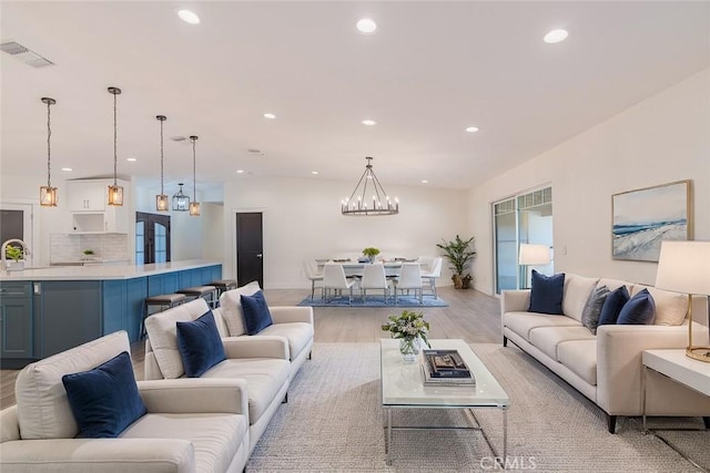 living room with sink, a chandelier, and light hardwood / wood-style flooring