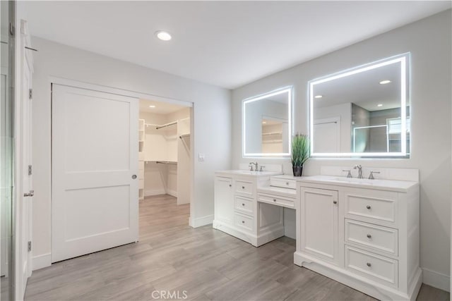 bathroom featuring a shower with shower door, hardwood / wood-style flooring, and vanity