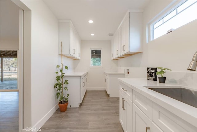 kitchen with light hardwood / wood-style flooring, white cabinets, and sink