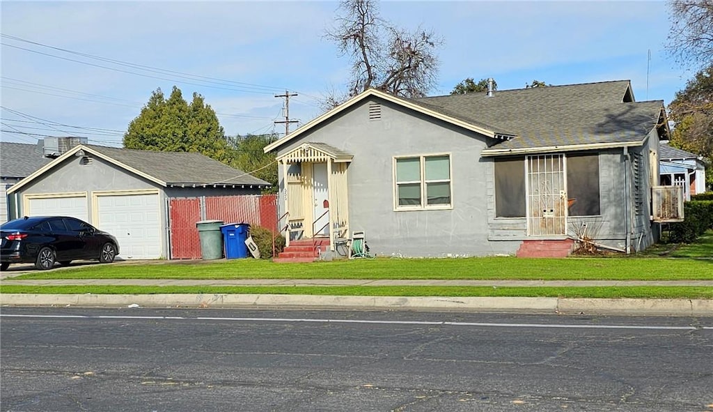 view of front facade with a front lawn, a garage, and an outdoor structure