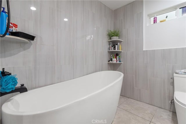 bathroom featuring toilet, tile walls, tile patterned floors, and a bathing tub