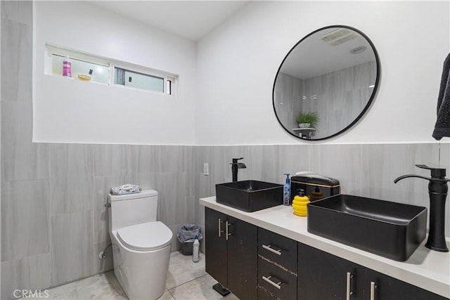 bathroom with toilet, tile walls, tile patterned flooring, and vanity