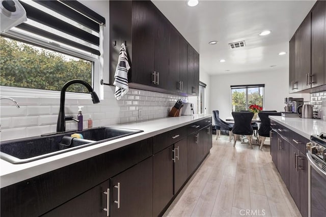 kitchen with dark brown cabinets, tasteful backsplash, and sink