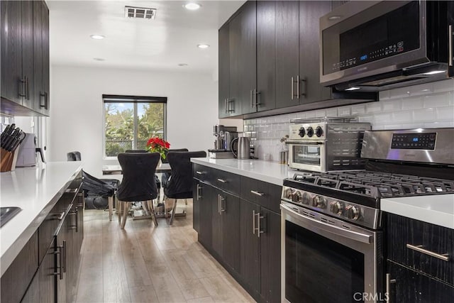 kitchen featuring tasteful backsplash, light hardwood / wood-style floors, stainless steel appliances, and dark brown cabinetry