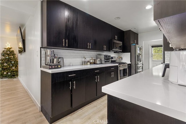 kitchen featuring light wood-type flooring, backsplash, and stainless steel appliances