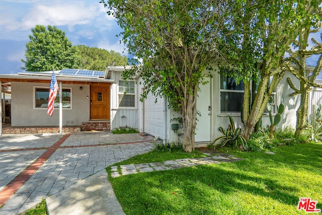 view of front of property featuring a front lawn and solar panels