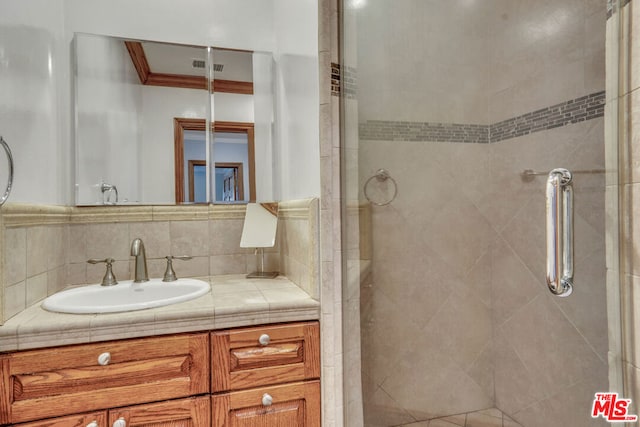 bathroom featuring a shower with shower door and vanity