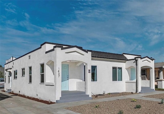 view of front of house featuring crawl space, a tiled roof, and stucco siding