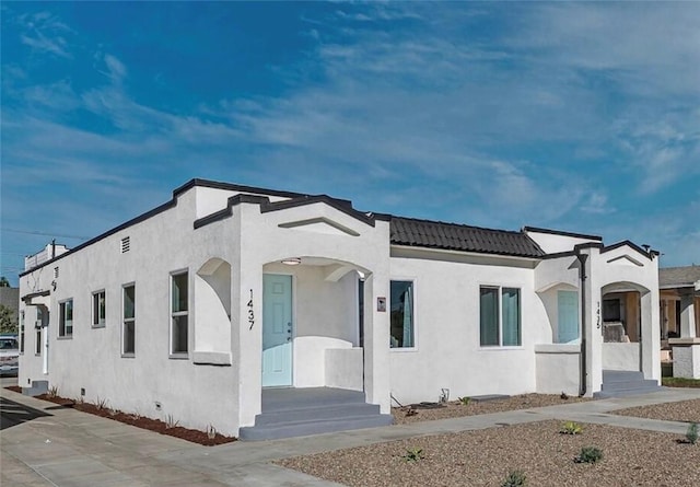 mediterranean / spanish house with stucco siding and a tiled roof