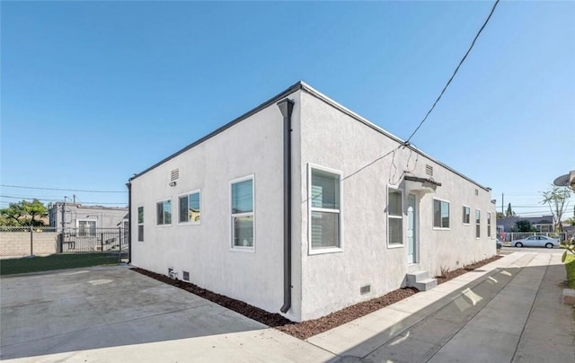 view of property exterior with crawl space, fence, and stucco siding